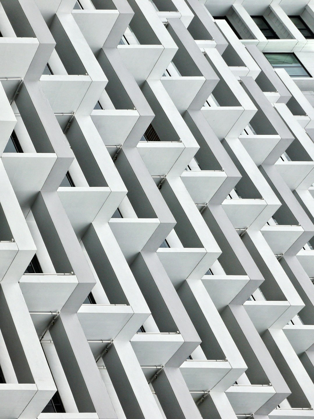 White angular architecture building facade with repeating pattern of triangles in a white and grey color palette, photographed at high resolution in the style of photography.