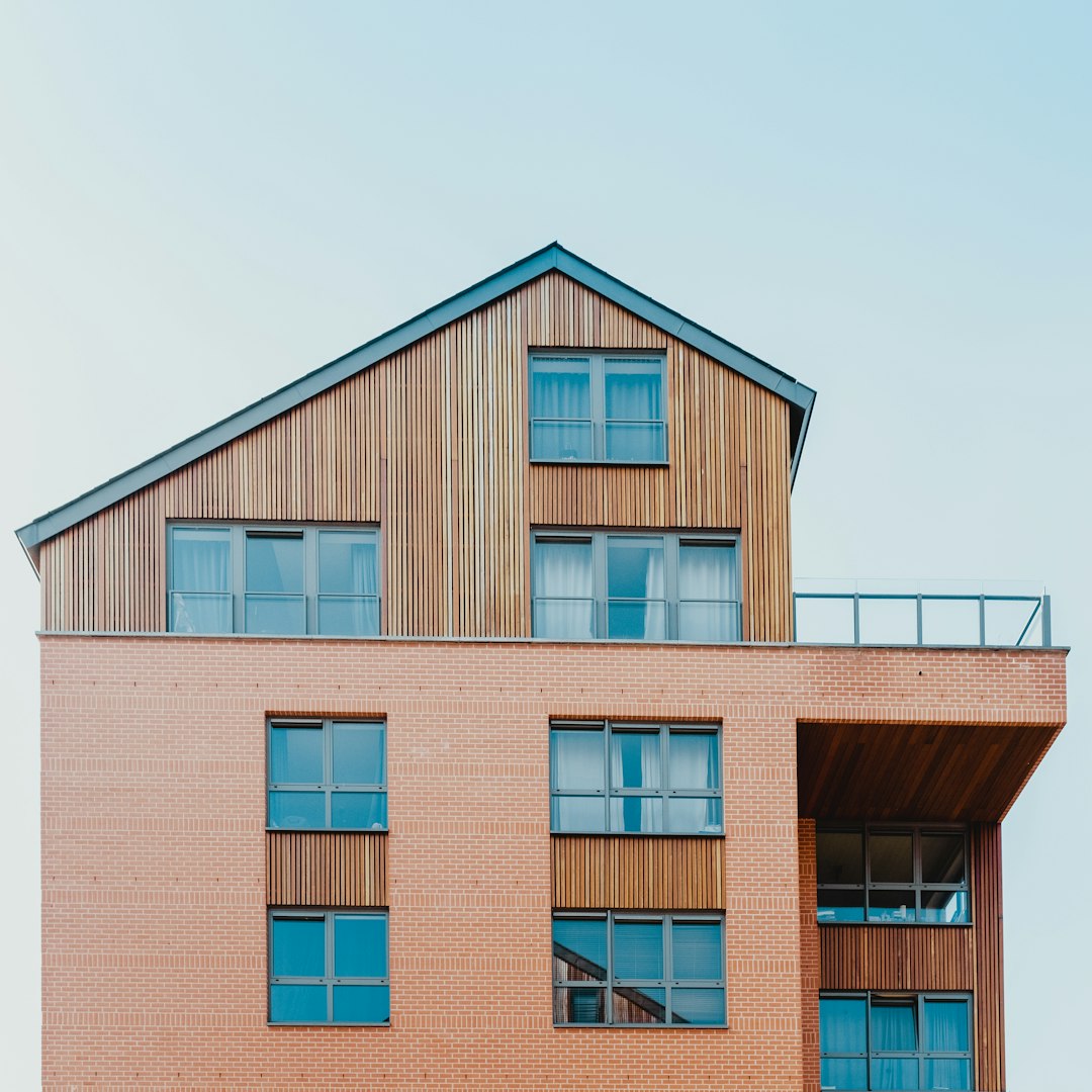 Photo of a modern apartment building in the style of red brick and wood, in the scandinavian architectural style, front view, minimalist architectural style, blue sky, natural light, neutral colors, photo in the style of Canon EOS R5 at F8, ISO100, 24mm f/9