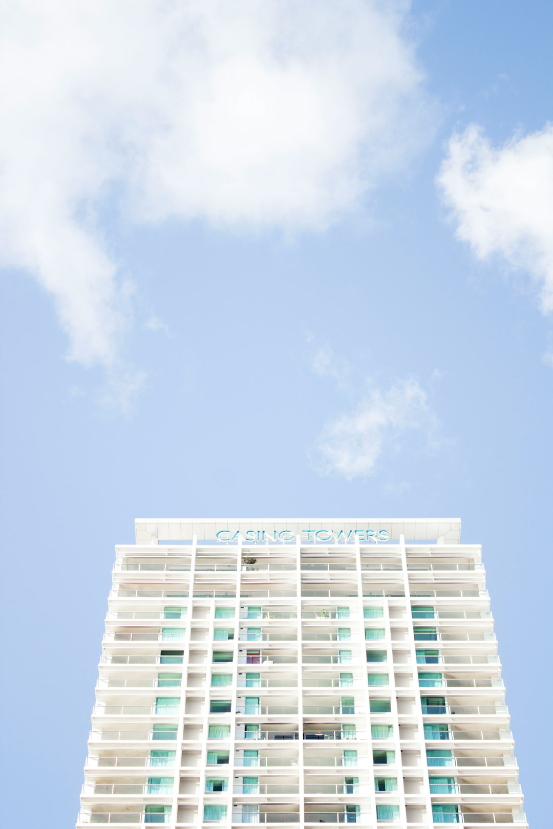 Photography of a white building with a blue sky, written on the top “KA_Game Tower”, a high rise hotel in Miami Beach, with bright colors, green and turquoise details, in a minimalistic architectural style, capturing a summer mood, with sunlight and soft pastel colors, utilizing natural lighting, with clouds in the background, in the style of [Iwan Baan](https://goo.gl/search?artist%20Iwan%20Baan), taken with a 35mm lens. –ar 85:128