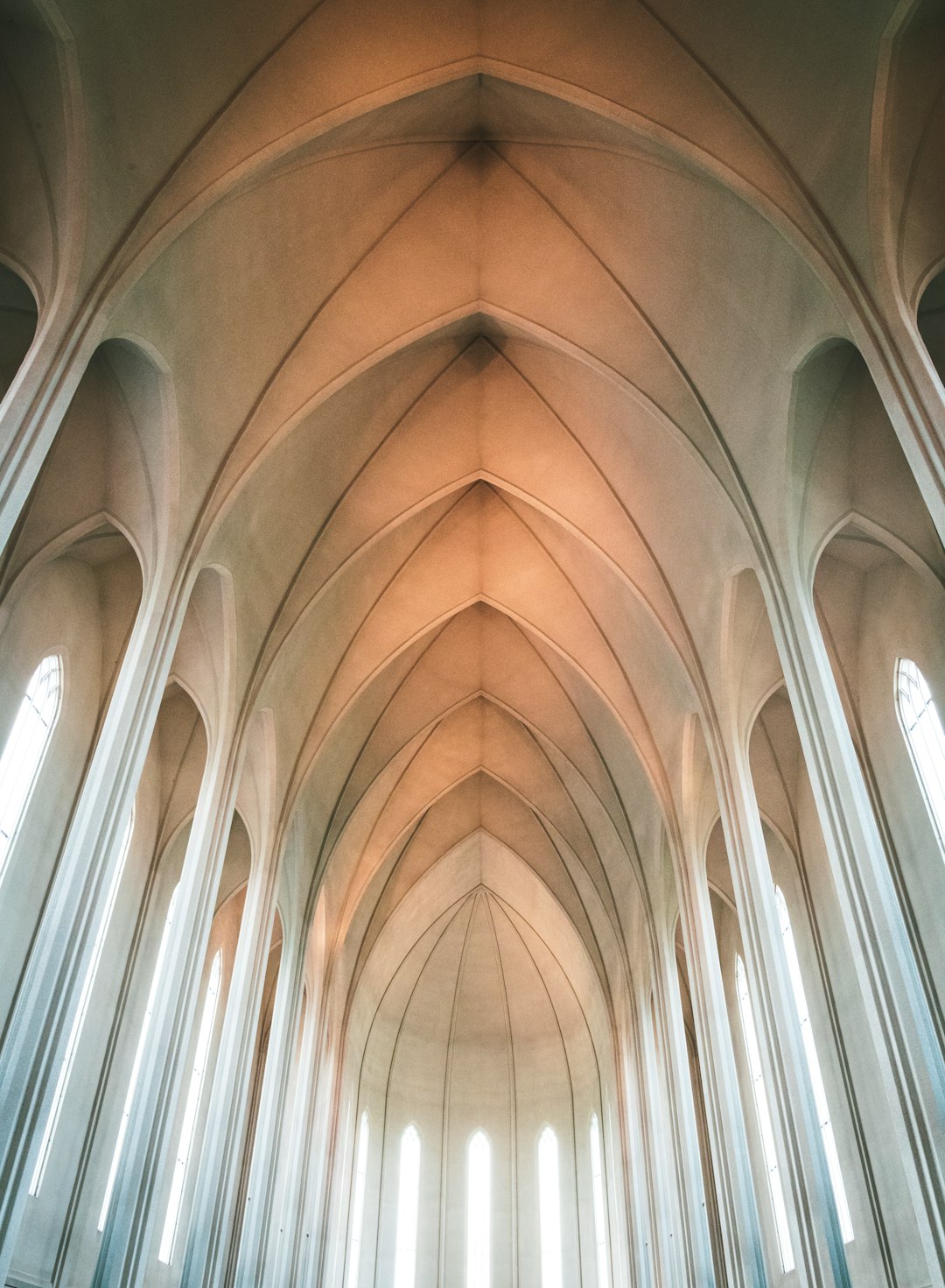 low angle photo of the ceiling inside Hallgrímskirji church in Iceland, light coming through windows, soft lighting, beige color palette, symmetrical composition, high resolution photography