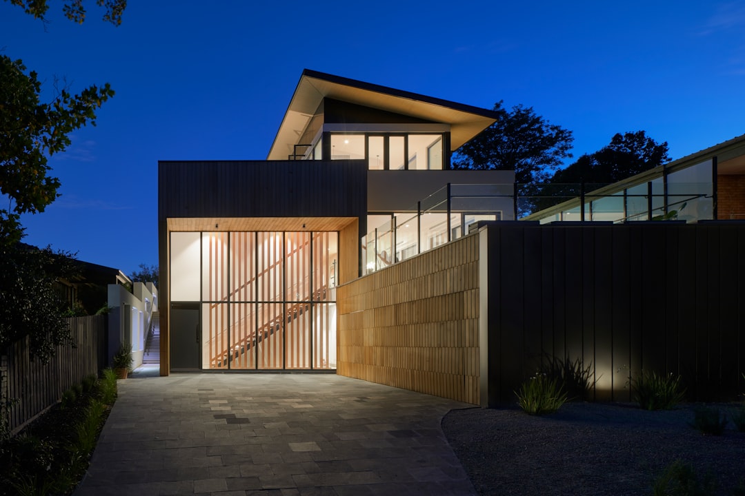 Modern two story house with dark wooden slats on the front wall, located in East Brptistuc california, night time, blue hour, architectural photography –ar 128:85