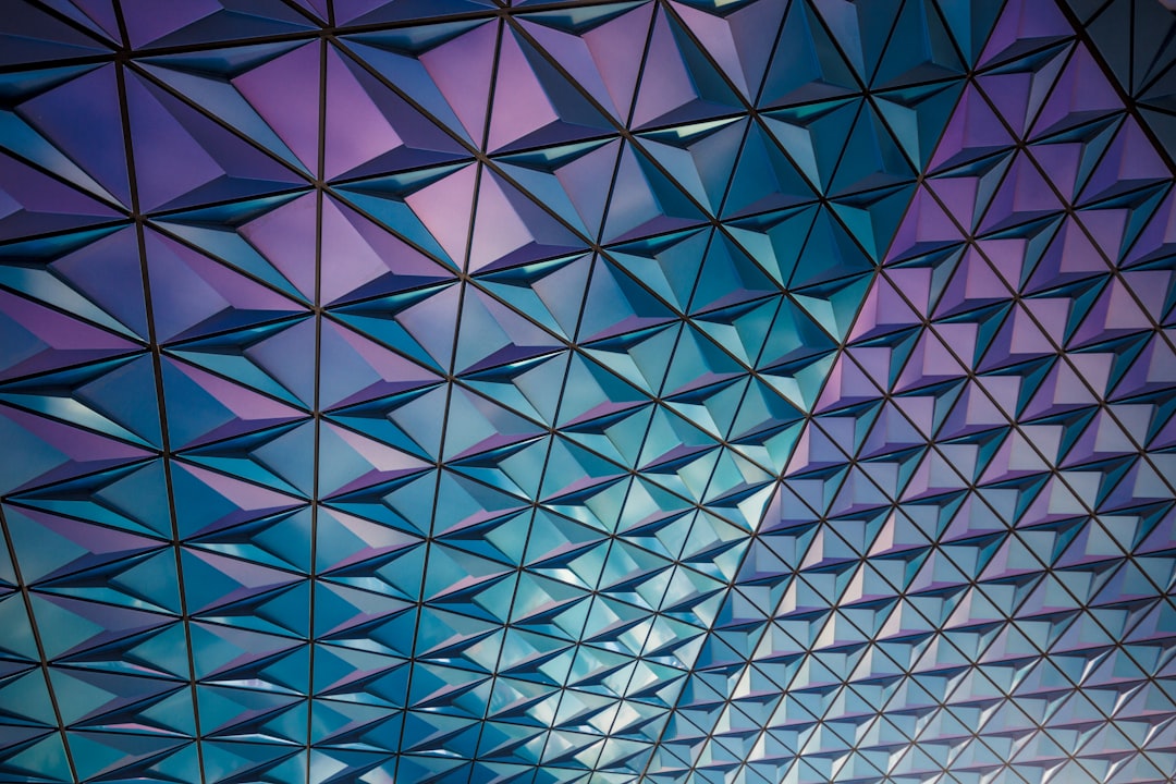 Geometric pattern of the roof of Disney’s Epcot Center, glass material, blue and purple gradient color scheme, overhead shot angle, closeup view of the geometric structure on one side of an outdoor ceiling, high resolution photography, interior design magazine style, detailed architecture. The camera is located at eye level. High definition photography in the style of an interior design magazine. –ar 128:85