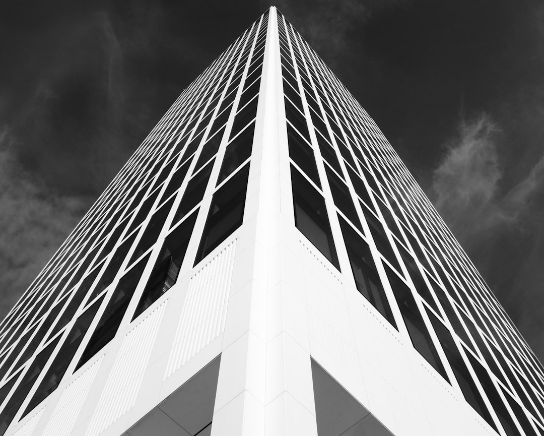 Black and white photograph of the corner tower in stark contrast to its surroundings, emphasizing clean lines and sharp edges, architectural photography, high resolution, high detail, hyper realistic, captured with Canon EOS5D Mark III camera, f/8 aperture, 30mm focal length, tower’s silhouette against a dramatic sky, highlighting the modernist design elements, emphasizing symmetry and simplicity, skyscraper architecture