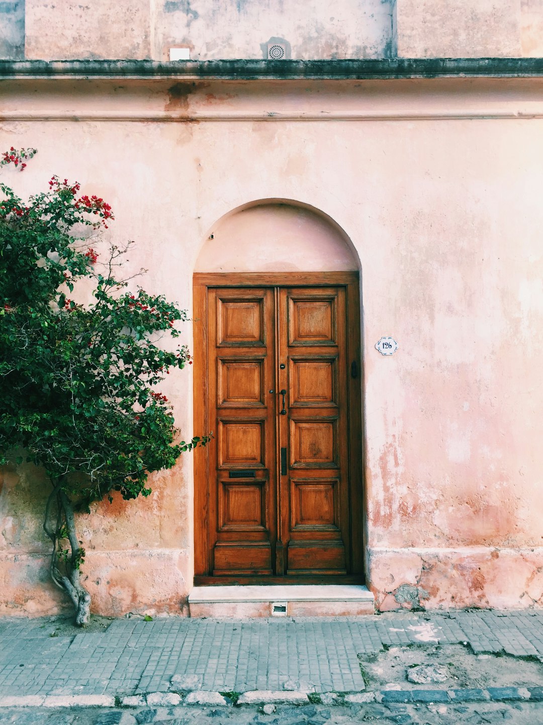 A wooden door of an old house in Spain, pastel pink walls, shot on Kodak film, Instagram aesthetic, unsplash photography style, minimalism, in the style of minimalism.