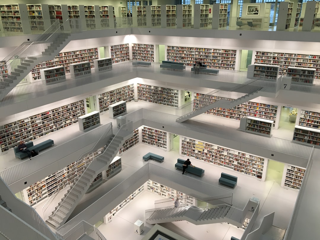 A white library with many books and multilevel shelves and staircases in the center, a very realistic photography from an aerial view captured with a wide angle lens on a DSLR camera, in the style of an unnamed artist.