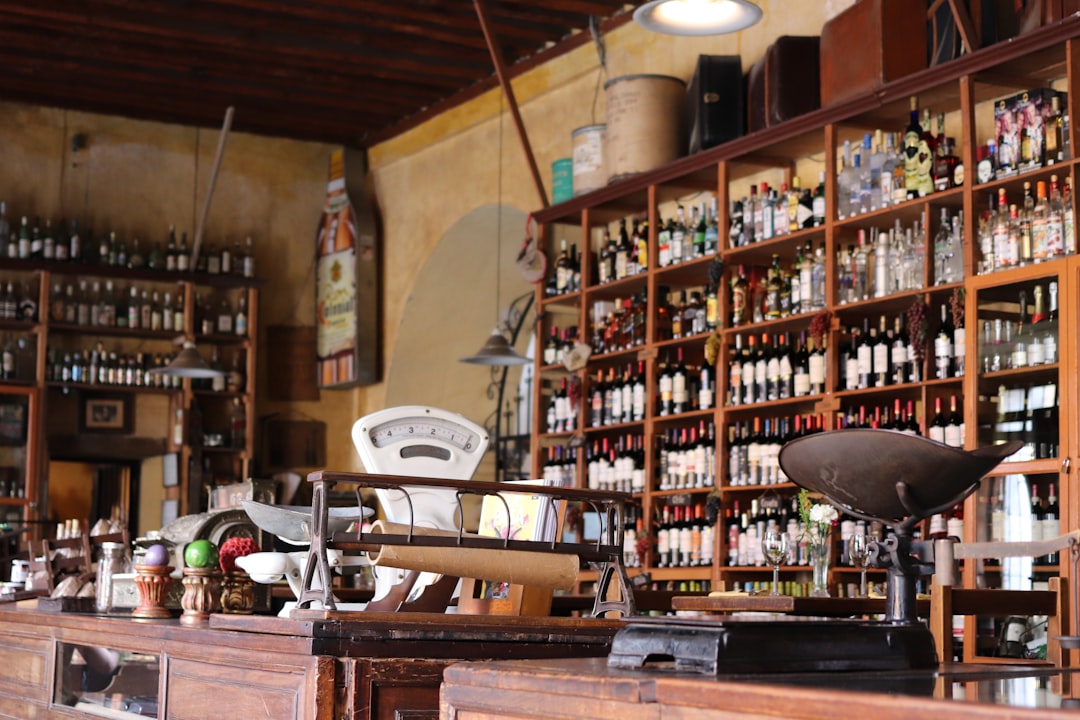 The interior of an old-fashioned general store was depicted in the style of GuanAbsolute vintage, with shelves lined up full of bottles and antiques, a large scale on the counter for weighing items, creating a nostalgic atmosphere. –ar 128:85