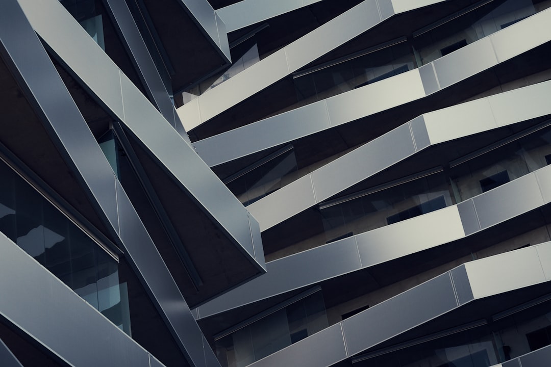 A closeup of the exterior facade of an office building in New York City, featuring angular lines and silver metal accents. The focus is on its geometric design with sharp angles and curves that create visual depth. In contrast to traditional architecture, it has modern elements such as glass windows and metallic details. This photo highlights how architectural innovation can shape cityscapes in the style of modern elements. –ar 128:85