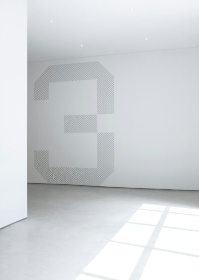 A large white wall with the number "3" in an interesting and modern font, with a light gray dot pattern on it, in a minimalist style, with large space between elements, with light from the window on the left side, with a light floor and white walls.