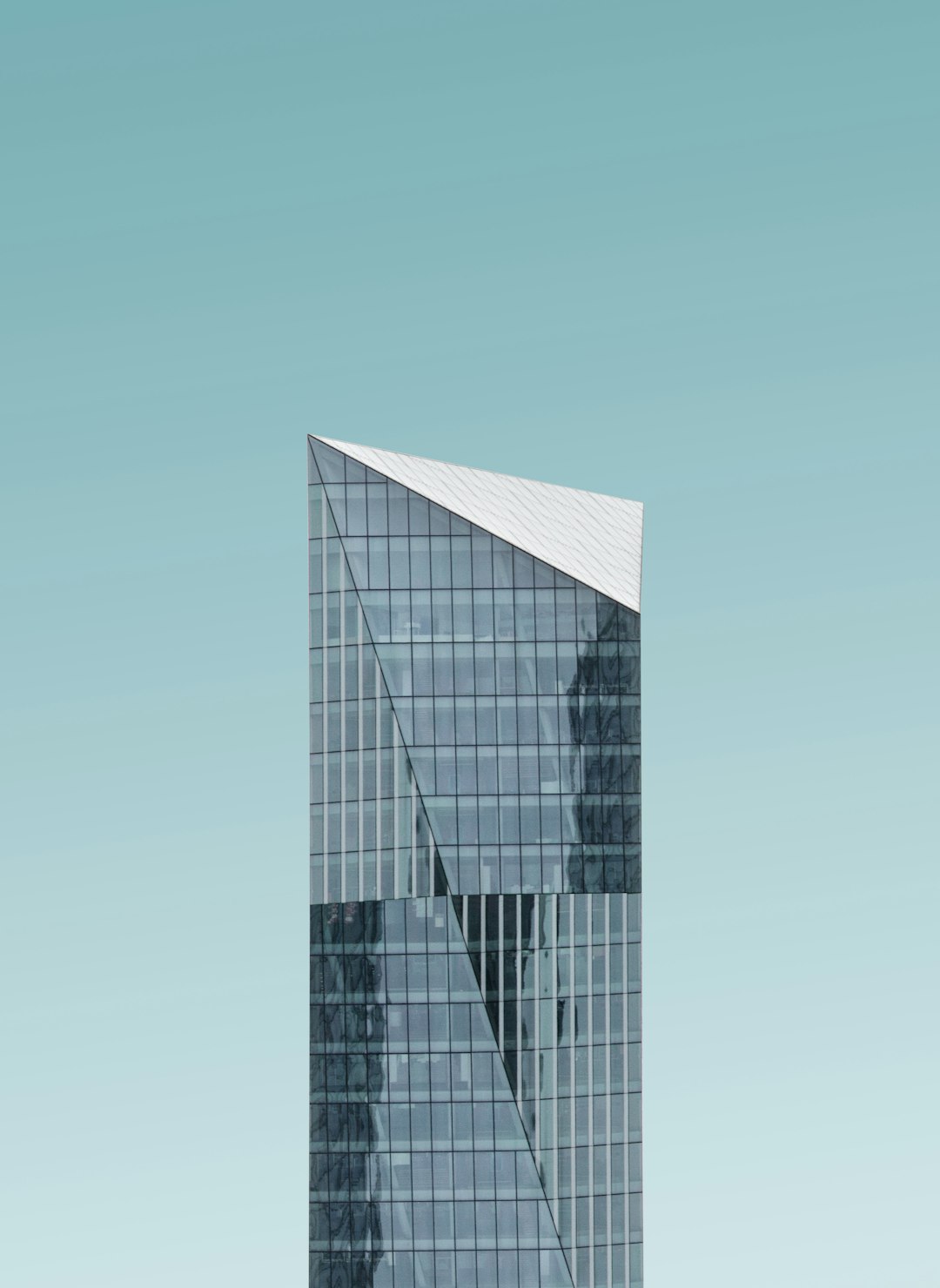 A tall glass building with a triangular shape at the top, with a sky blue background, architectural photography in the minimalist style, depicting modernist architecture and architectural design in the minimalist style, with high resolution and super detail, of the highest quality with high details, at 8k resolution. –ar 93:128