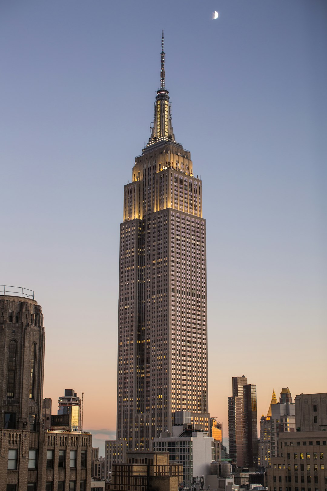 empire state building in new york city, full view, at dusk, clear sky, golden hour, moon in the background, photorealistic, in the style of canon eos r5 –ar 85:128