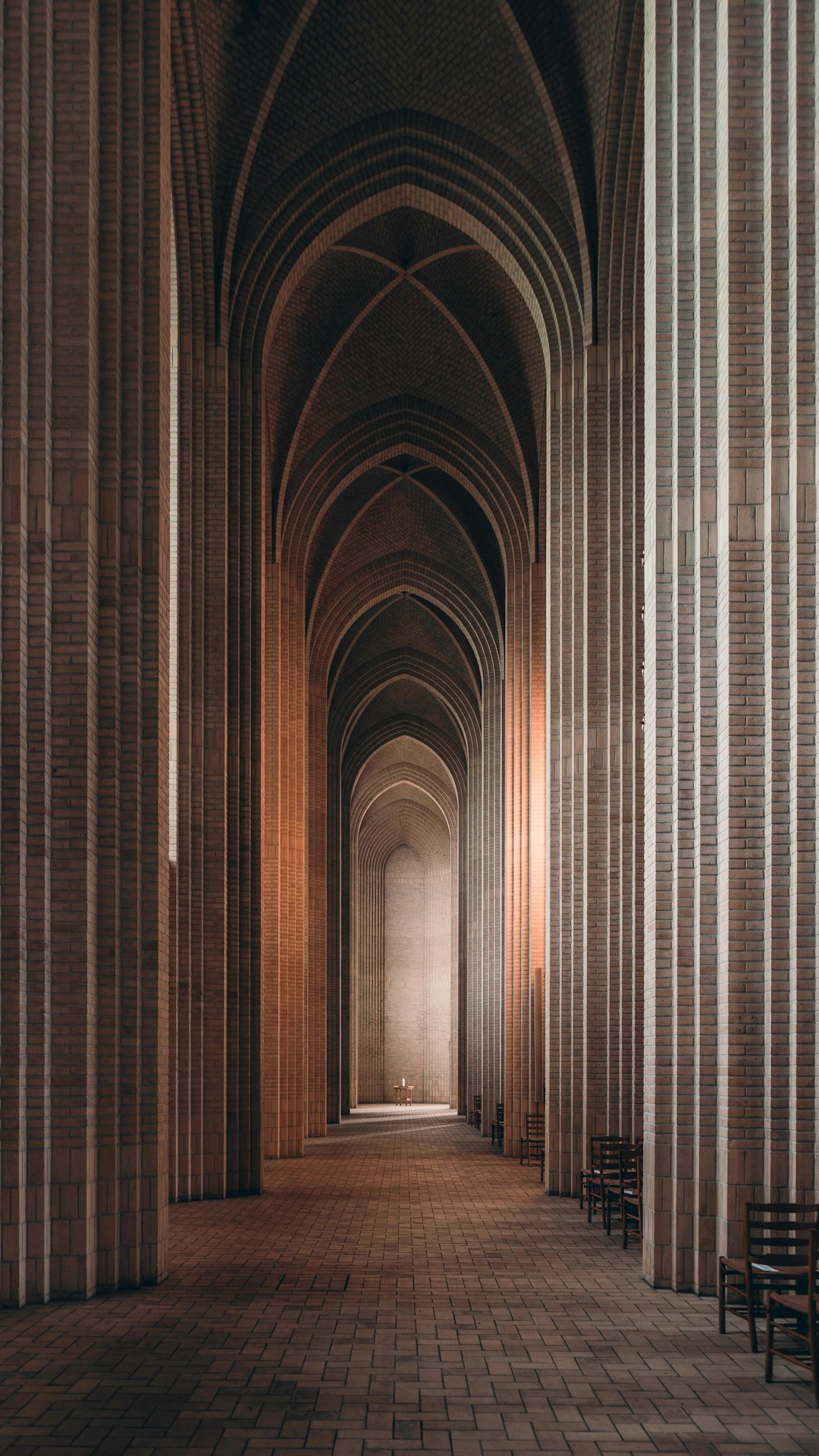 An architectural photograph of the interior of Grsequence church in the style of Hippolyte. It shows a minimalist brutalist architecture with tall columns and arches made from red bricks. The light is soft, and it’s a golden hour. There are no people in the frame. It feels quiet and contemplative. –ar 9:16