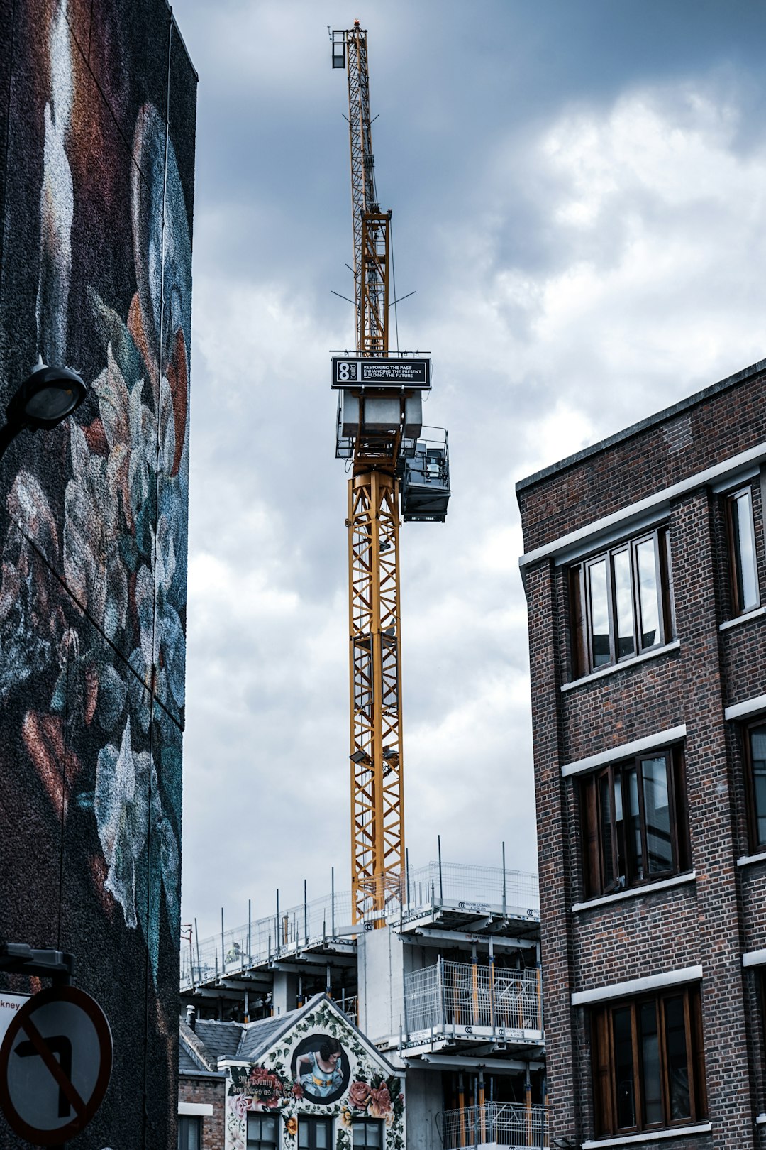 photo of a modern crane in the city center, a dutch street with graffiti on buildings, a cloudy sky, during the daytime, Canon dslr photography in the style of unknown artist –ar 85:128