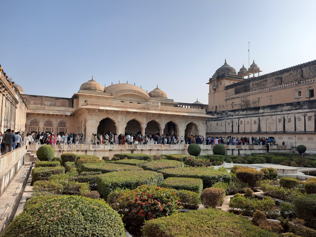 A view of the busy courtyard at Amber Fort palace with people, bushes and plants in the style of Clef. –ar 4:3