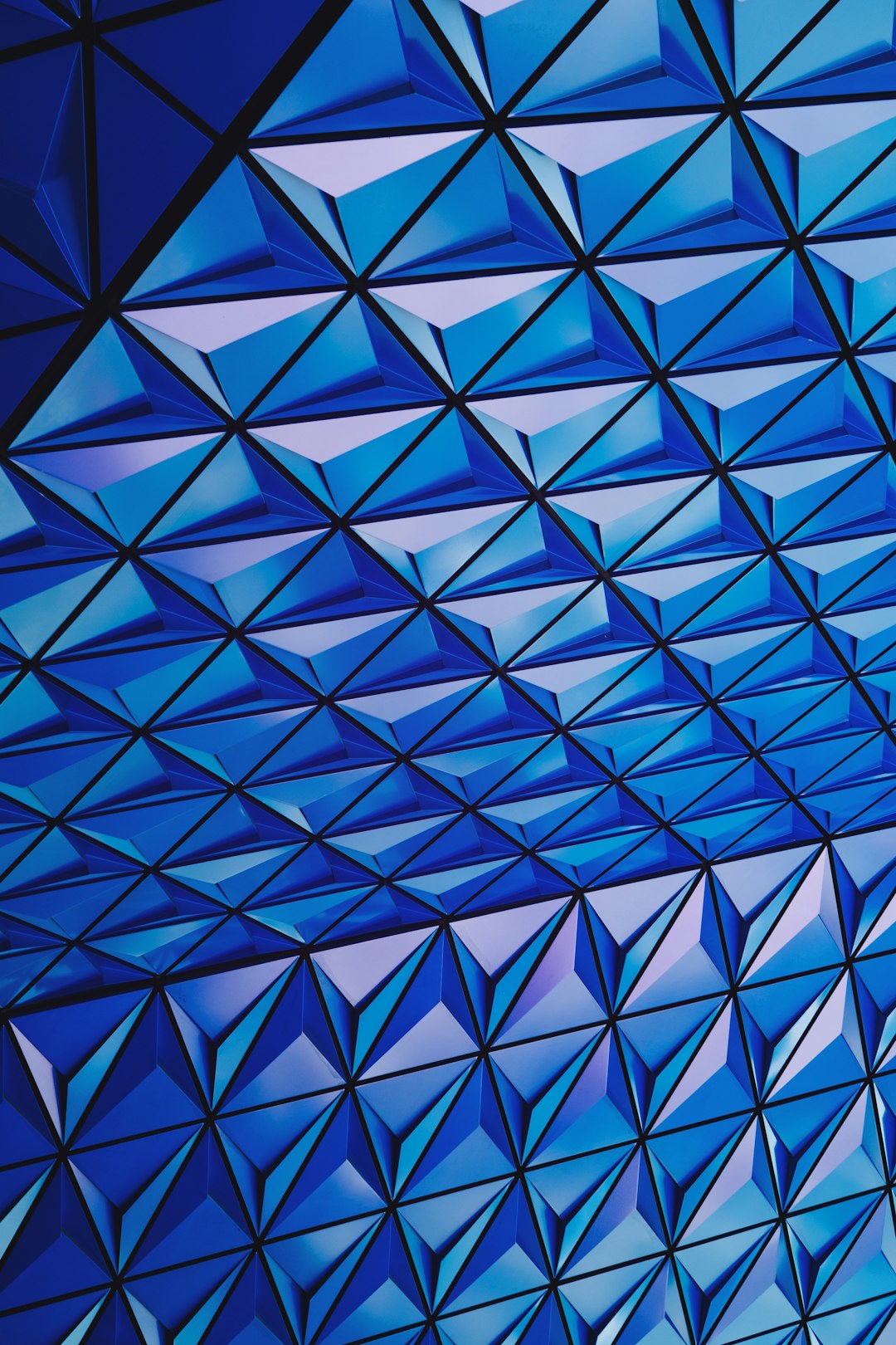 Blue geometric triangle pattern on the ceiling of the Disney Space Coast in the style of hyper realistic photography. –ar 85:128