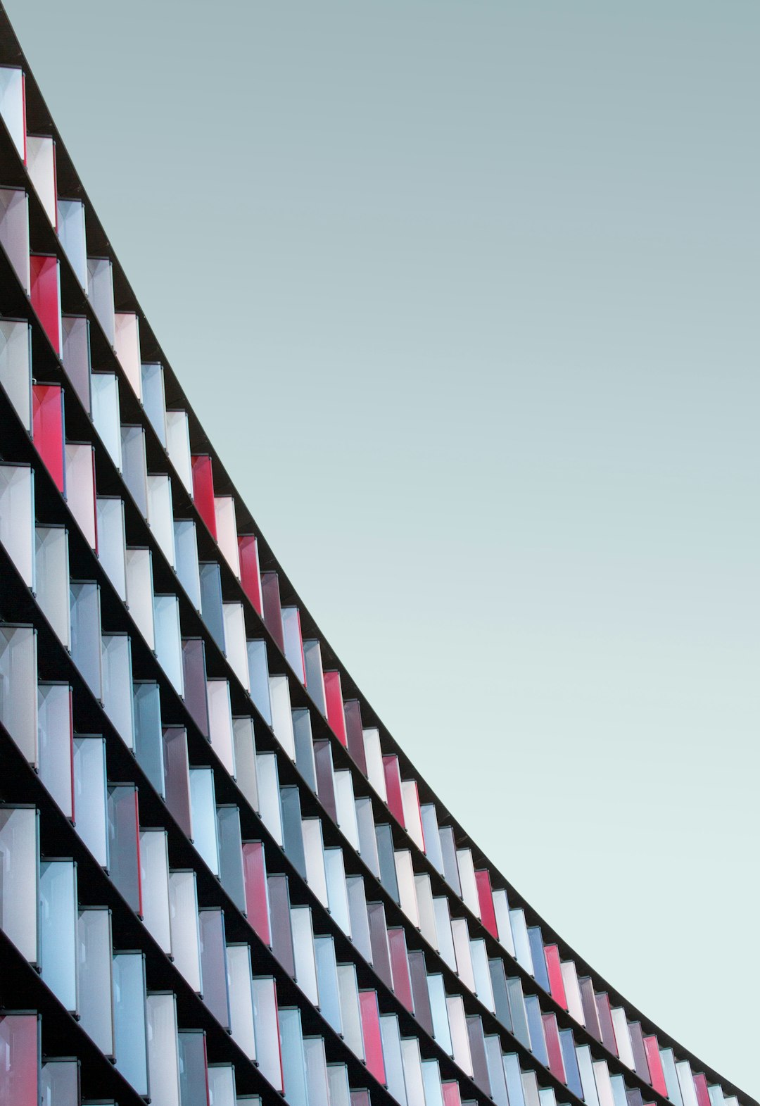 photography of a curved facade, made with a geometric pattern and color blocks in red, white, blue and grey colors, architecture photography, archdaily, daylight, minimal background, in the style of minimal editing of the original text.