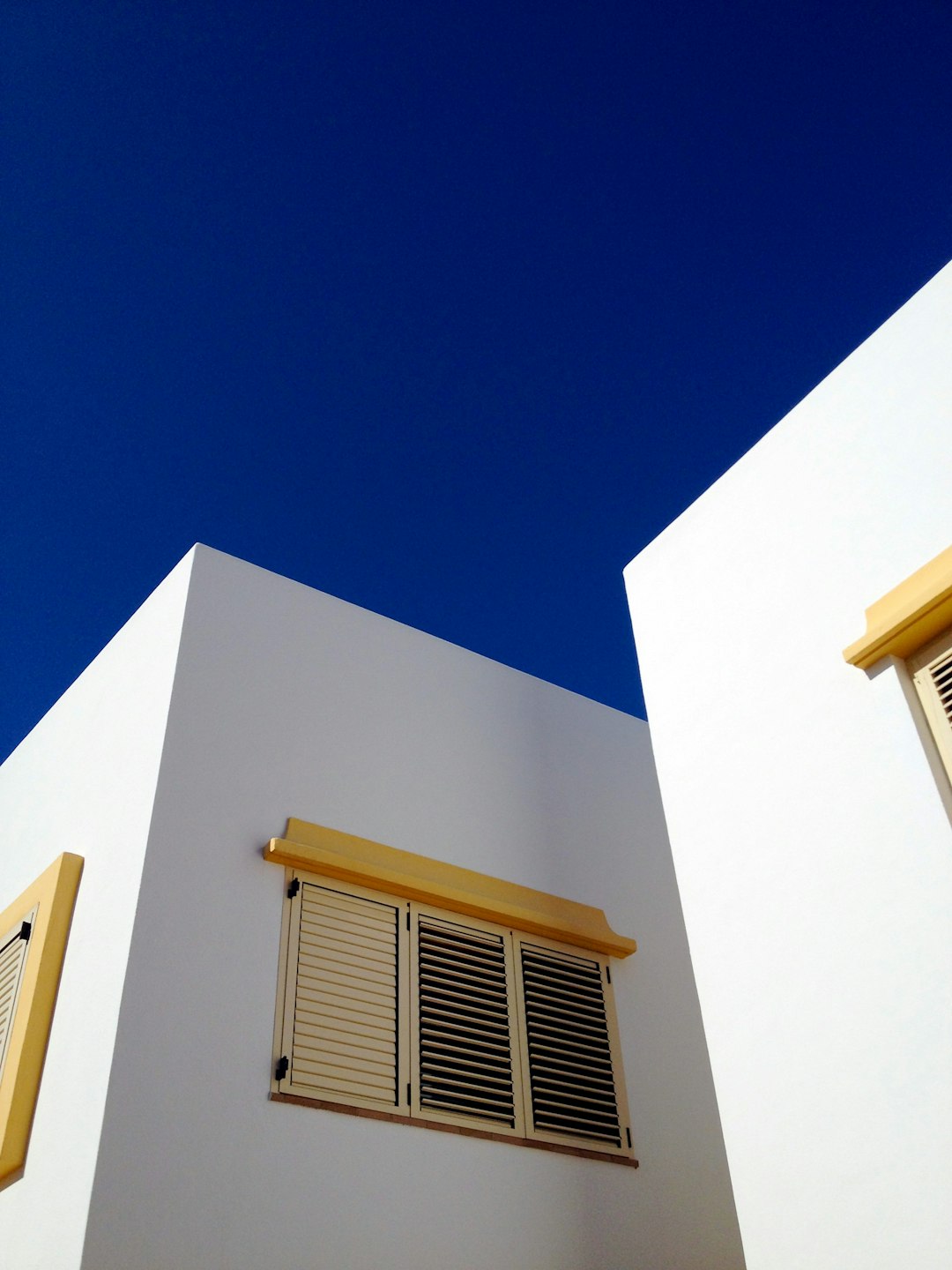 A photo of minimalistic architecture in Algarve, with white walls and blue shutters and a blue sky, in sharp focus and high resolution and high quality. –ar 3:4