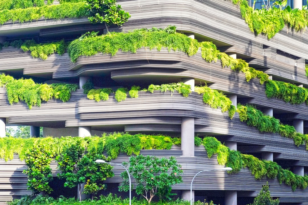 A modern eco-friendly building with greenery on the balconies, featuring sustainable architecture in Singapore in the style of ecoarchitecture. –ar 128:85