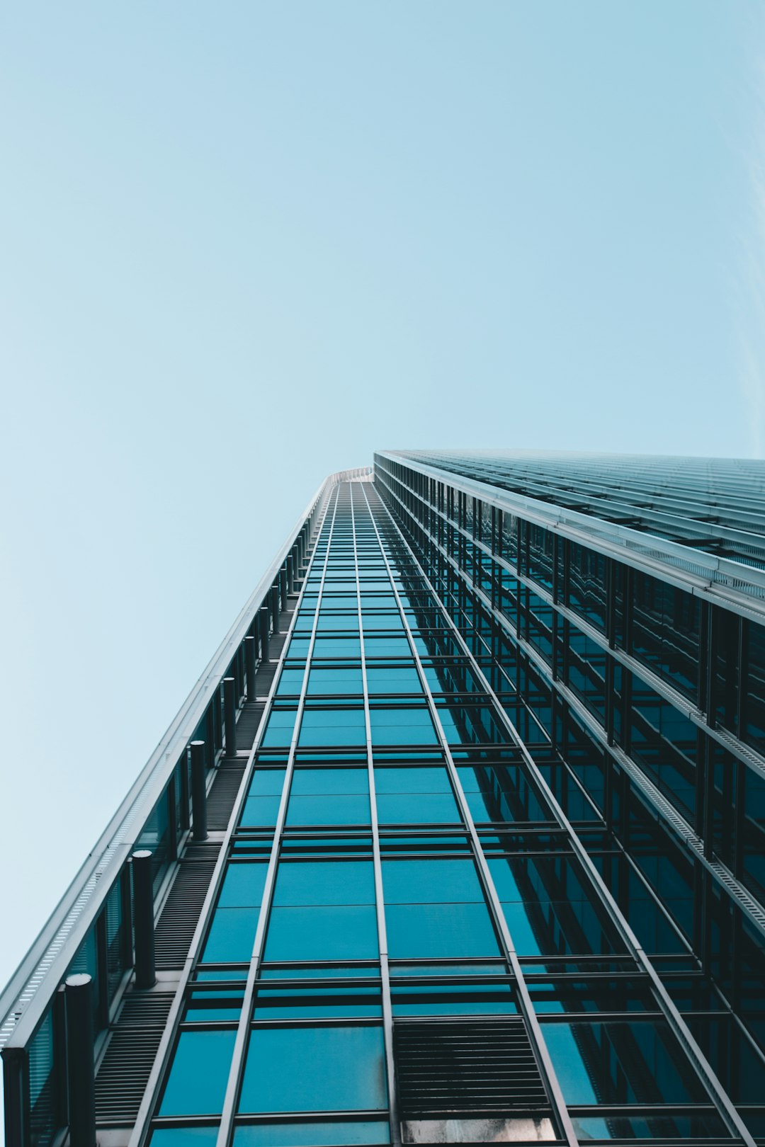 A tall glass building, looking up at the sky from below, in the style of unsplash photography, minimalism, blue colors, high resolution