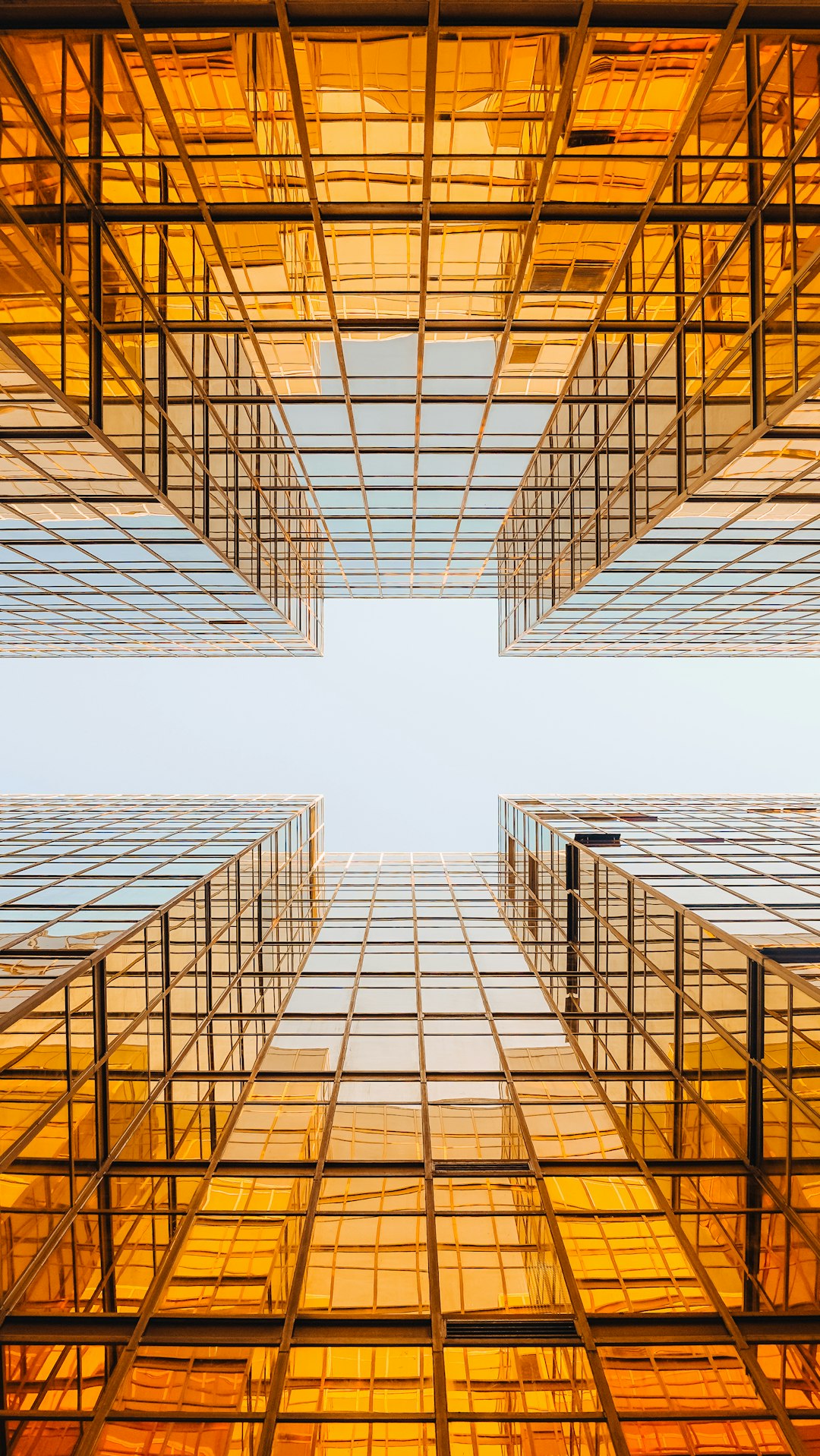 A photograph of the bottom view of two glass skyscrapers in an orange sky, with a symmetrical composition, in the style of architectural photography, in an epic photo.