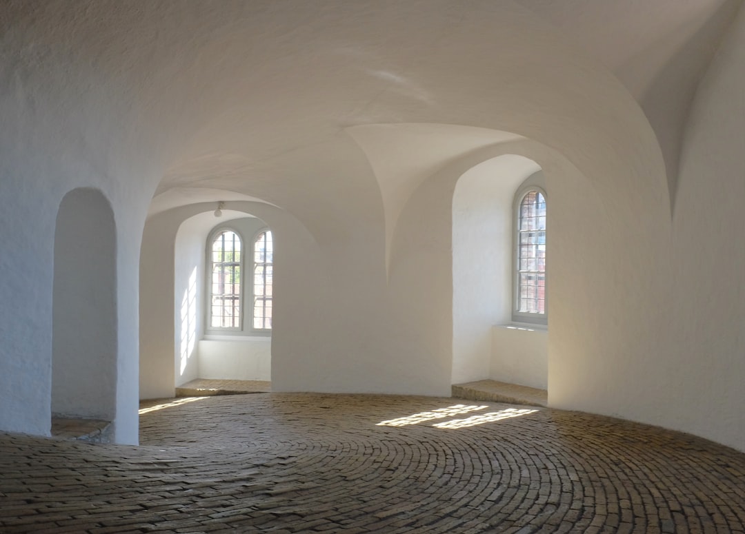 The interior of the white tower at Copenhagen’s Rosenborg Castle in closeup, with its arched windows and ancient brick floor, offering an empty space for creative design elements in the style of the artist. –ar 128:91