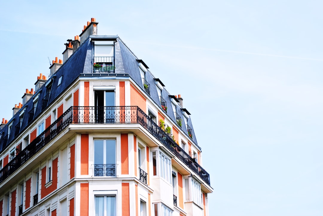 Beautiful apartment building in Paris, closeup of corner with blue roof and white walls with orange stripes, blue sky background, no people or cars visible, focus on the architectural details, natural daylight, clear skies, high resolution photography in the style of no artist. –ar 128:85