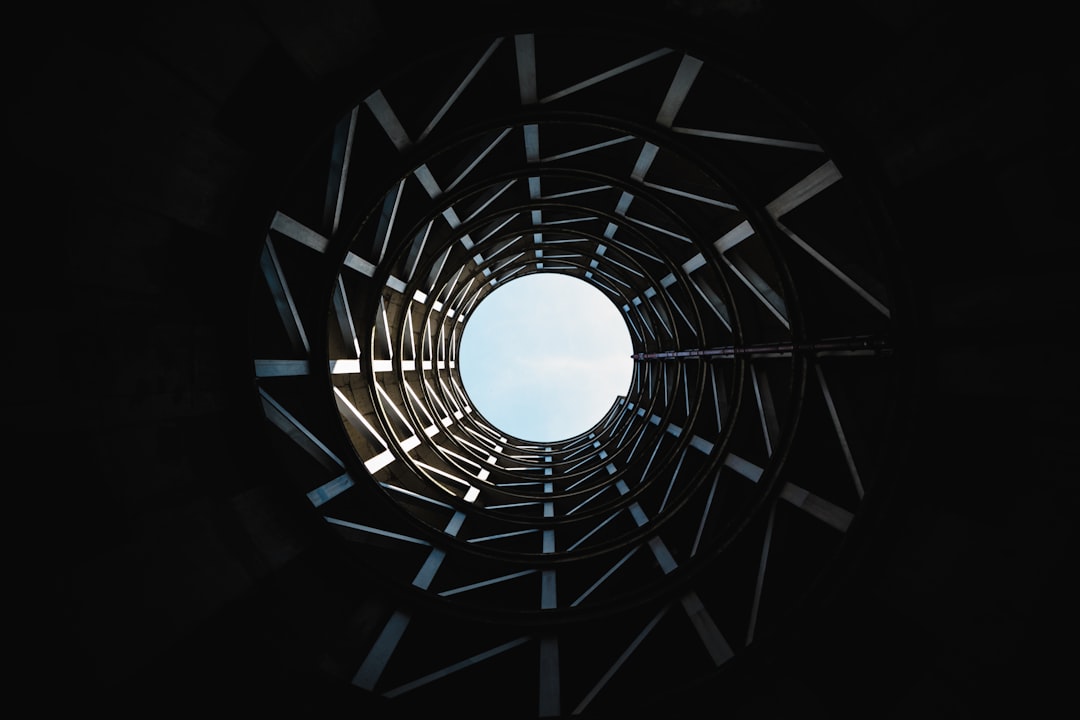 photo of the inside view through a tall circular steel tower, low angle shot, black background, daylight