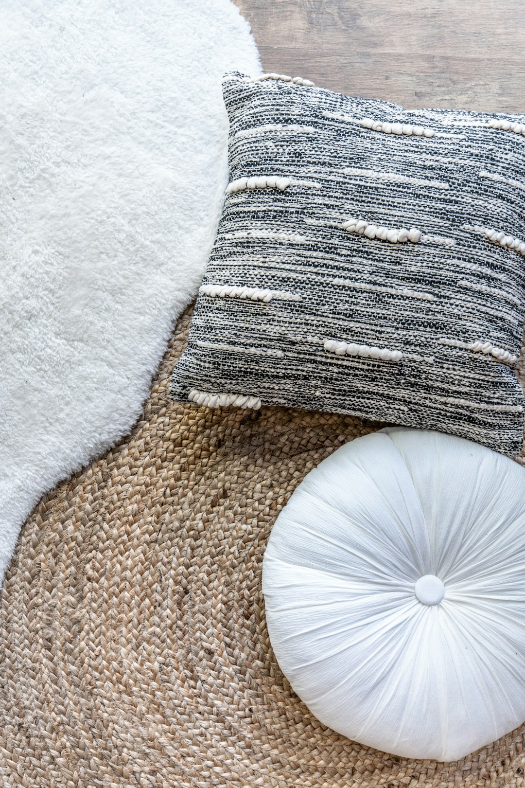 A white round cushion and grey woven fabric pillow on top of the jute rug, with a natural texture background, boho style home decor photography in the style of natural light, with high resolution. –ar 85:128