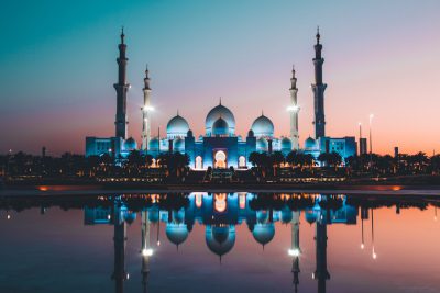 Photo of the Sheikh Zayed Mosque in Abu Dhabi at night with reflection on water, in the style of unsplash photography, blue and white colors, evening light, wide angle