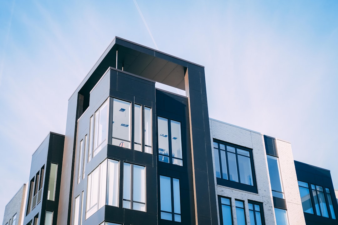 modern residential building, photo of a modern apartment complex exterior with large windows, a black and white color scheme, a clear blue sky, shot in the style of Sony Alpha A7 III –ar 128:85