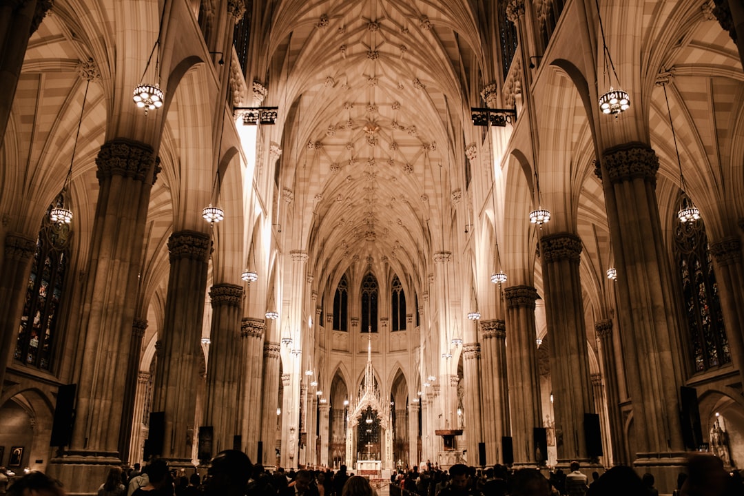 St Patrick’s Cathedral, New York City, wedding ceremony inside the grand and majestic cathedral. People in festive attire attended amid the dark ambiance with warm lighting from chandeliers. Photography was shot on a Canon EOS5D Mark IV with an EF lens to capture the ceremony in a cinematic style.