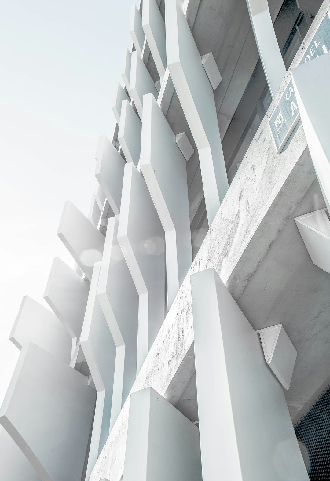 a white concrete parking garage made of interlocking angular shapes, designed by tadao andou, photographed from below, low angle, extreme close up, architectural photography, hyper realistic