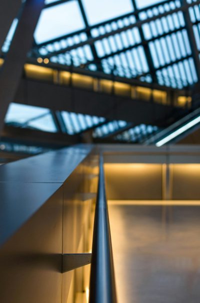 An overhead shot of the handrail in an office building, showcasing its sleek design and light features. The background is a glass ceiling with visible lighting that adds to the modern aesthetic. The focus on the handrails makes it stand out against the surrounding architecture. The photo captures the detail of the metalwork and how well-lit areas enhance the overall ambiance. Shot in the style of [Ansel Adams](https://goo.gl/search?artist%20Ansel%20Adams) using a Nikon D850, f/2 lens at 3 meters distance, 4D depth of field for a hyperrealistic effect.