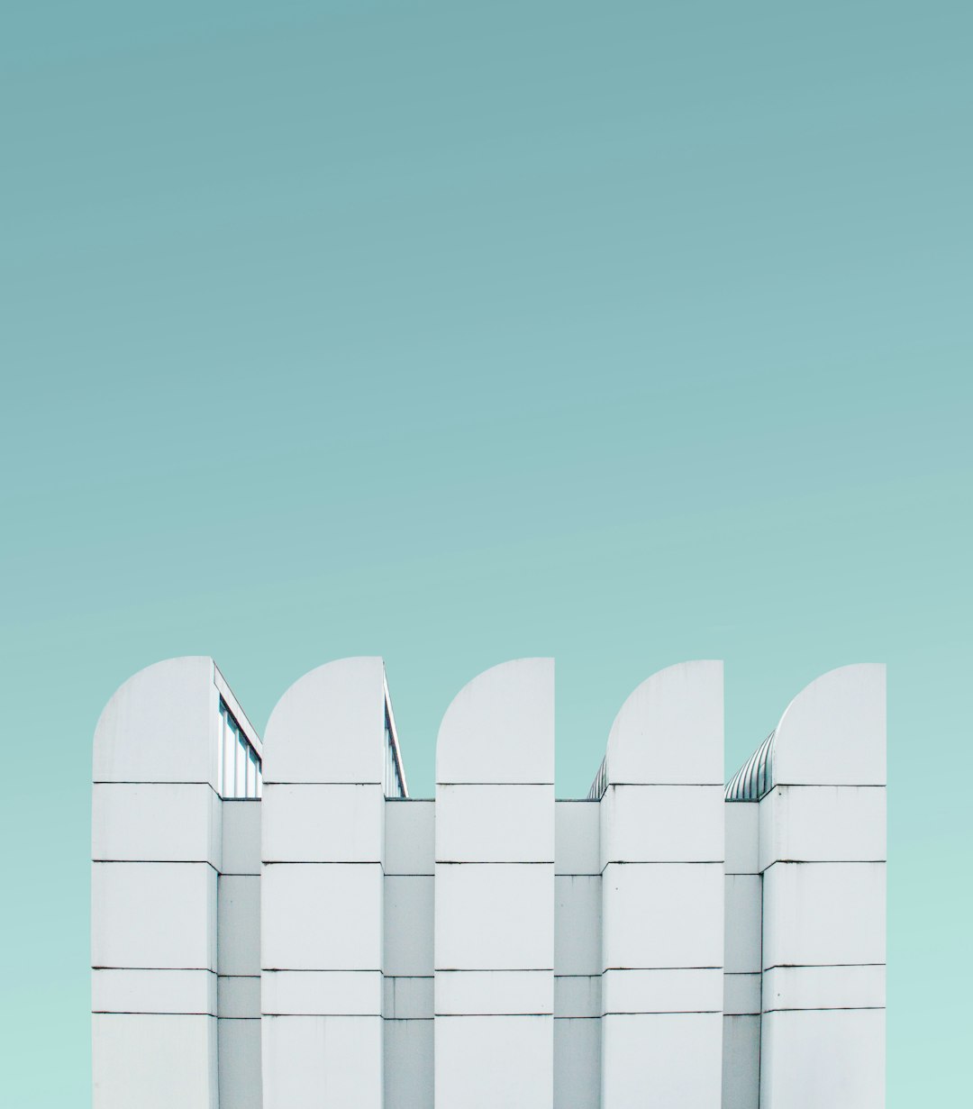 A minimalist composition featuring five white structures arranged in an artistic layout against the soft blue background of a clear sky, creating sharp contrast and adding depth to the scene. The minimalist aesthetic enhances simplicity while emphasizing architectural details. in the style of Jean Ciro photographer, unsplash