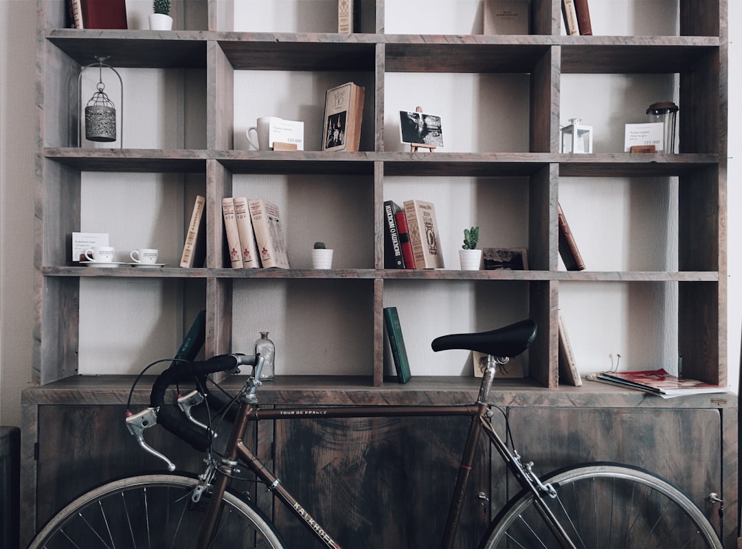 A photo of an apartment bookcase with books, coffee mugs and a vintage bike on the shelf, in the style of minimalism. –ar 64:47