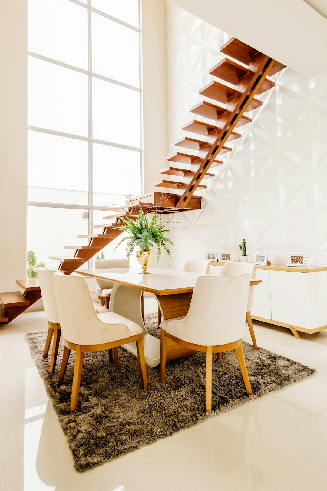 modern dining area with a table and chairs, a large window wall behind the staircase in white, carpet on the floor with a brown texture, the dining room is empty of furniture, a modern style home interior design with wooden elements, warm light from the windows –ar 85:128