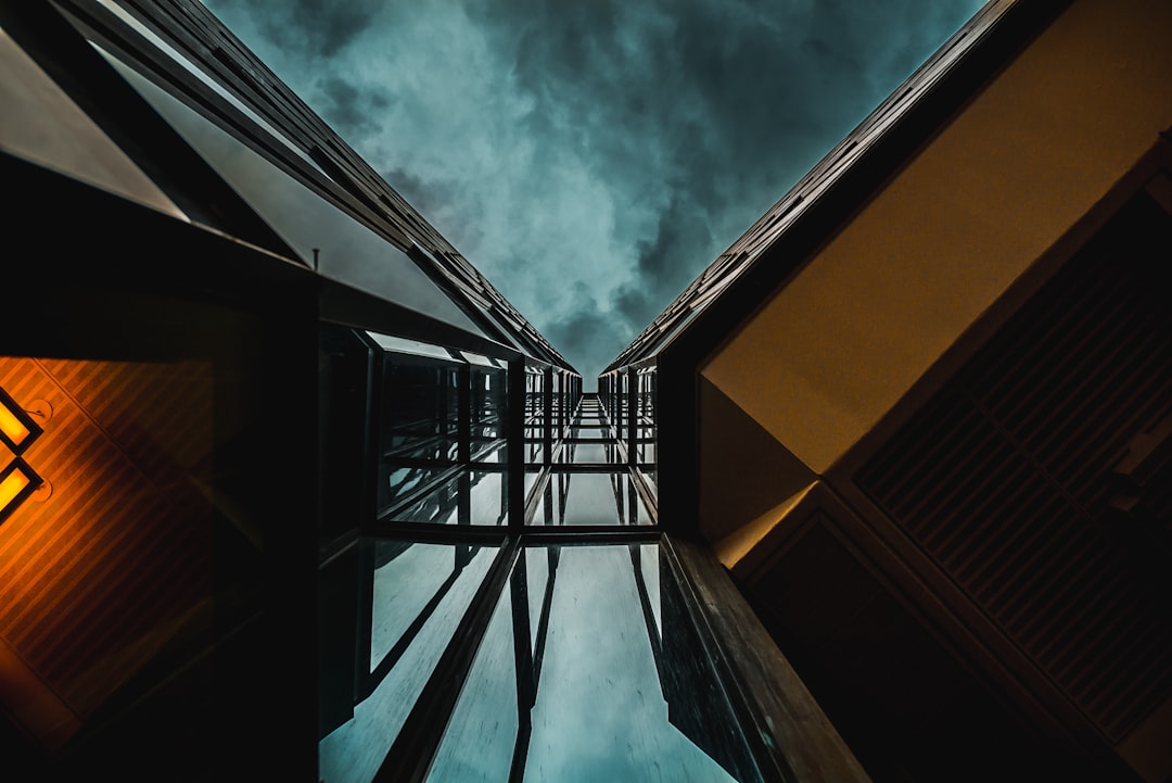 A photo of an overhead view looking up at the sky from between two modern buildings, dramatic lighting, dark clouds in background, shot on Sony Alpha A7 IV with f/2 lens