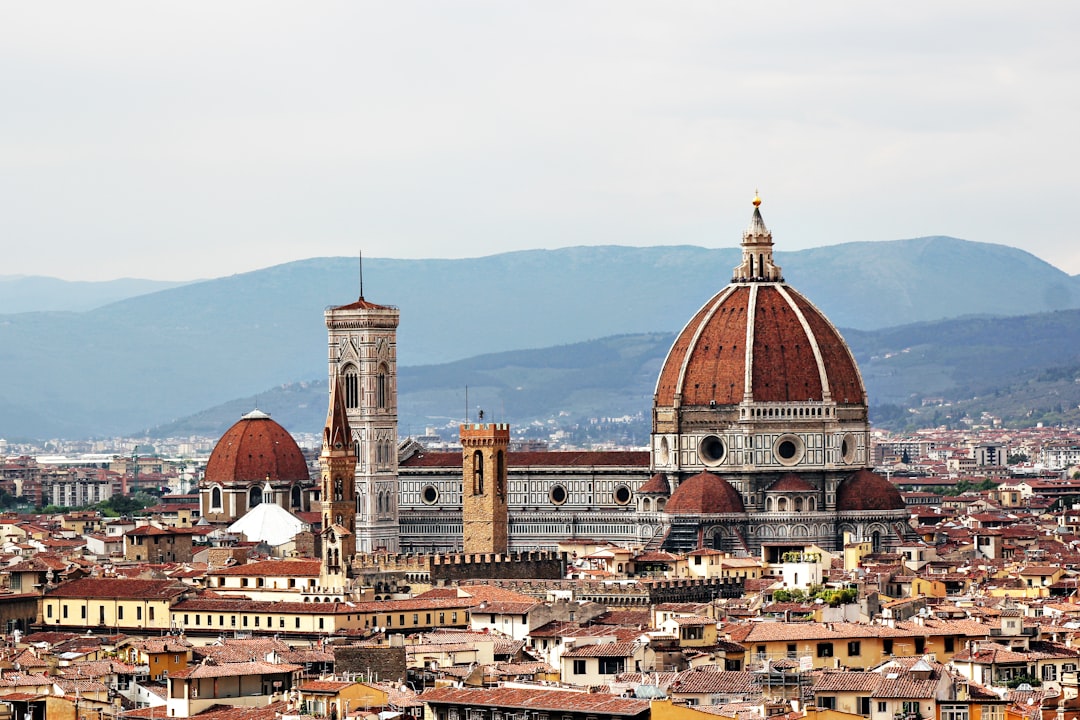 A panoramic view of the cityscape with iconic landmarks like Florence Cathedral, overlooking hills in background. The dome and spires stand out against the skyline, showcasing its architectural beauty. –ar 128:85