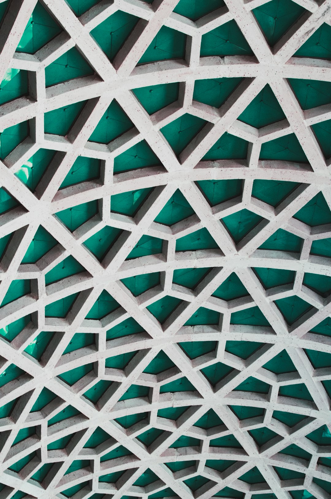 A white and green concrete wall with geometric patterns in the style of intricate geometry and Islamic architecture, shot on a Pentax camera.