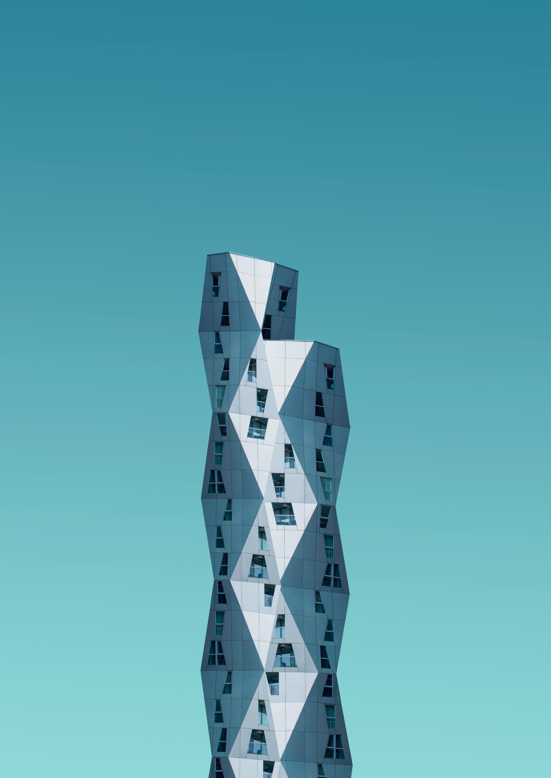 A tall building made of geometric shapes in a minimalist design with a blue sky background, photographed at high resolution in a hyper realistic, cinematic style. –ar 45:64