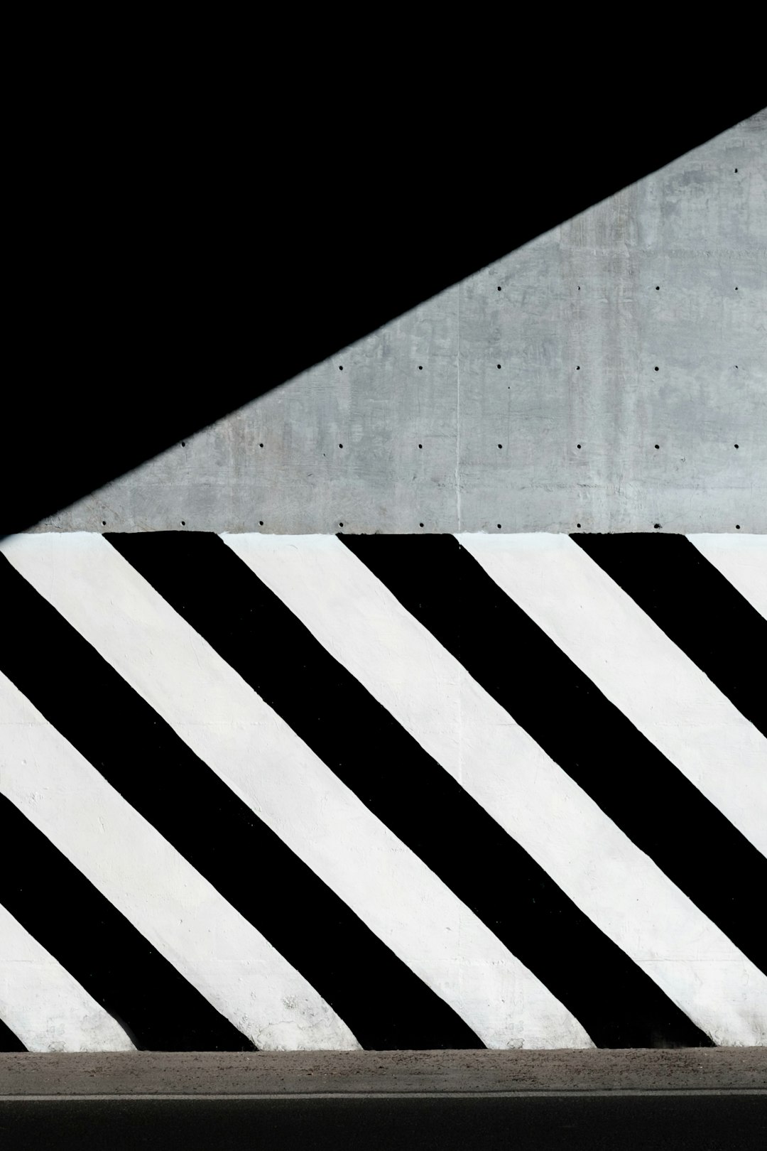 A minimalist composition of a wall with diagonal black and white stripes, creating an abstract urban background