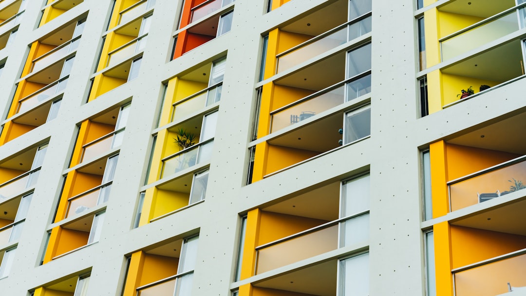 A close up photo of the facade of an apartment building with white and yellow panels, large windows with balcony doors, bright colors, modern architecture, architectural photography, archdaily, architectural detail in the style of archdaily. –ar 16:9