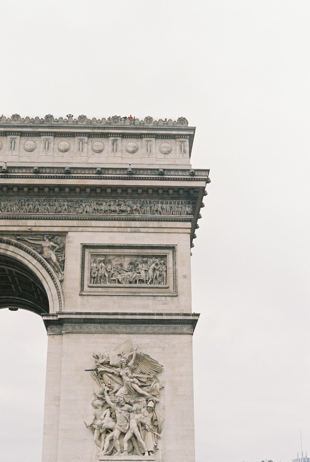 Close up of the Arc de Triomphe in Paris, white sky, muted tones, shot on film in the style of an old photograph.