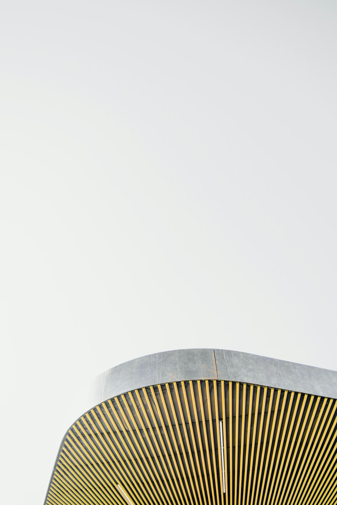 A photo of the top corner of an abstract modern minimalistic round building made from wood and concrete, on a light grey background, in a close up shot, in the style of architectural photography. –ar 85:128