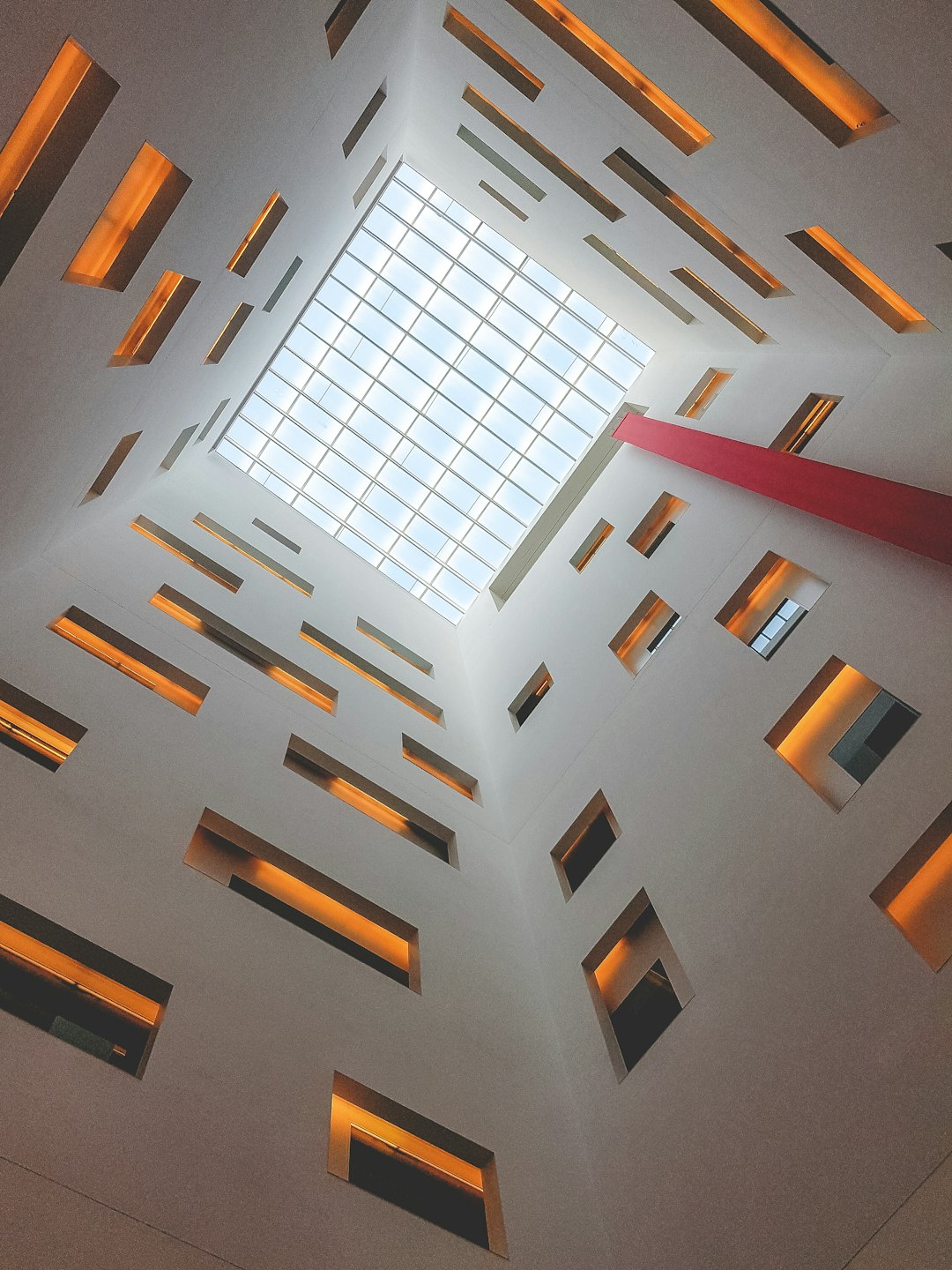 Photo of a skylight in the ceiling, interior design of modern architecture, skyscraper building, wide angle shot, window frames in different sizes and shapes, symmetrical, clean lines, white walls with red details, warm lighting. –ar 3:4