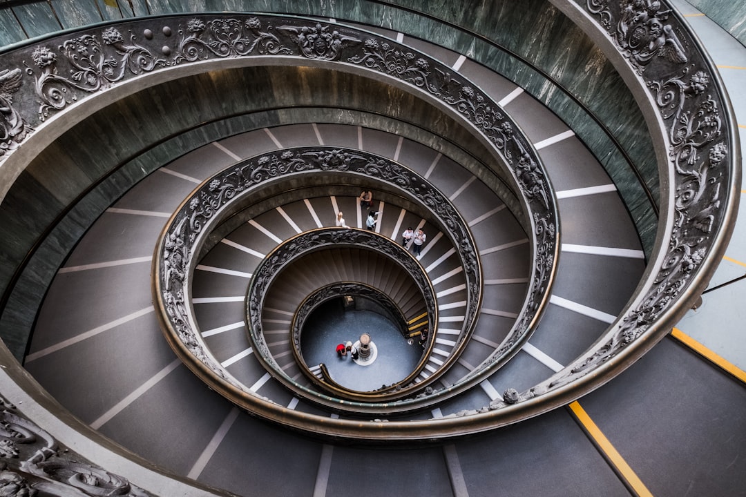 A spiral staircase in the Vatican with people walking up and down, viewed from above, in the style of Sony Alpha, realistic photography.