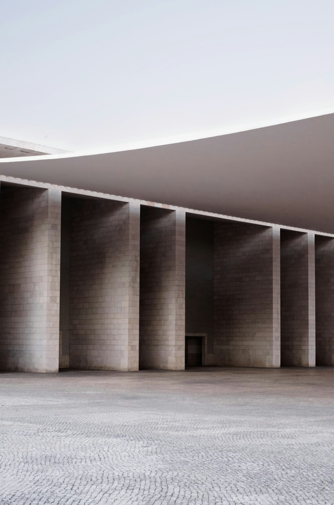 front view of an open and empty concrete courtyard with symmetrical columns, minimalist architecture in the style of [David Chipperfield](https://goo.gl/search?artist%20David%20Chipperfield), architectural photography, archdaily