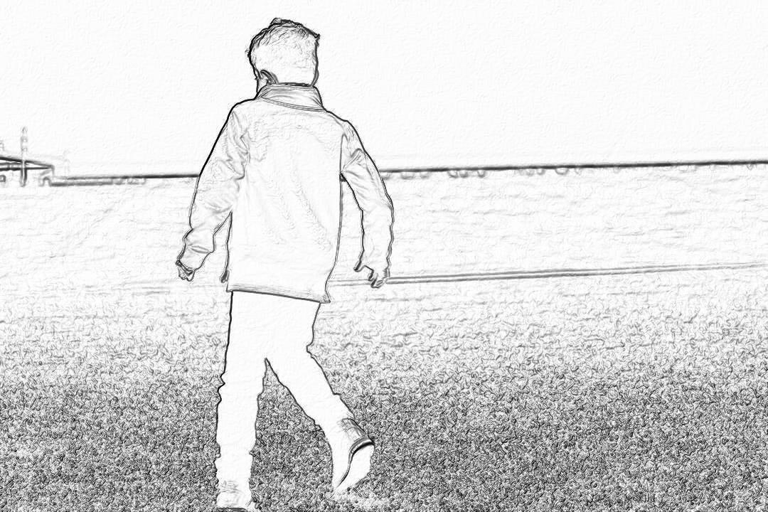 a black and white storyboard sketch of an over the shoulder shot of A young boy in jeans, long coat jacket walking on football field with his back to camera