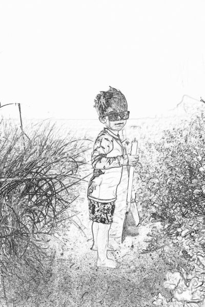 Black and white pencil sketch storyboard of a little boy wearing sunglasses, holding an iron sword in his hand standing on the beach with bushes behind him. The scene is captured from his side view. He wears shorts, a long-sleeved t-shirt and boots. There are some grasses around. No color. A simple drawing style. A low angle shot.