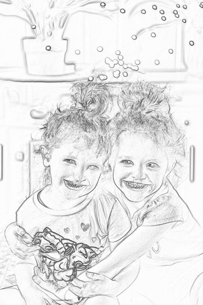 a black and white line art children's coloring book drawing of two smiling little girls with messy hair in pajamas, sitting on the floor playing at home. They have been eating chocolate chips from their small box full of them. The background is blurry and outoffocus. It has a whimsical feel to it.