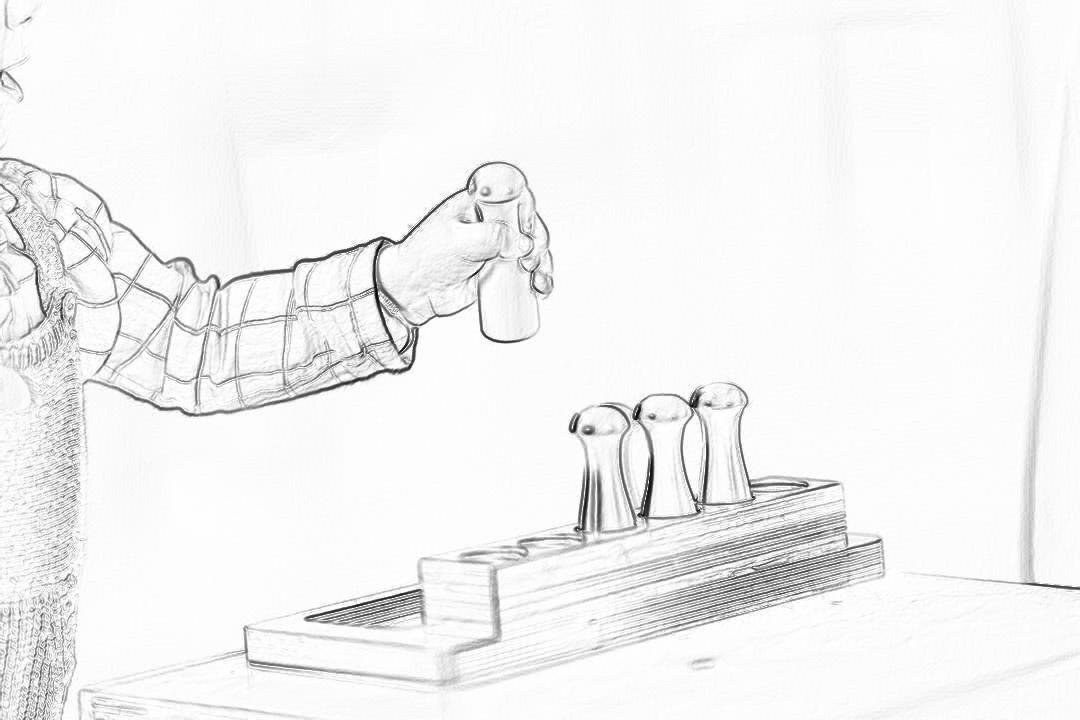 a simple pencil drawing of an arm with shirt sleeve, reaching out to place three wooden duck figures on top of the empty wood toy block in front of them. The hand is wearing plaid sleeves and has nails painted black. White background. Black ink. Simple line art.